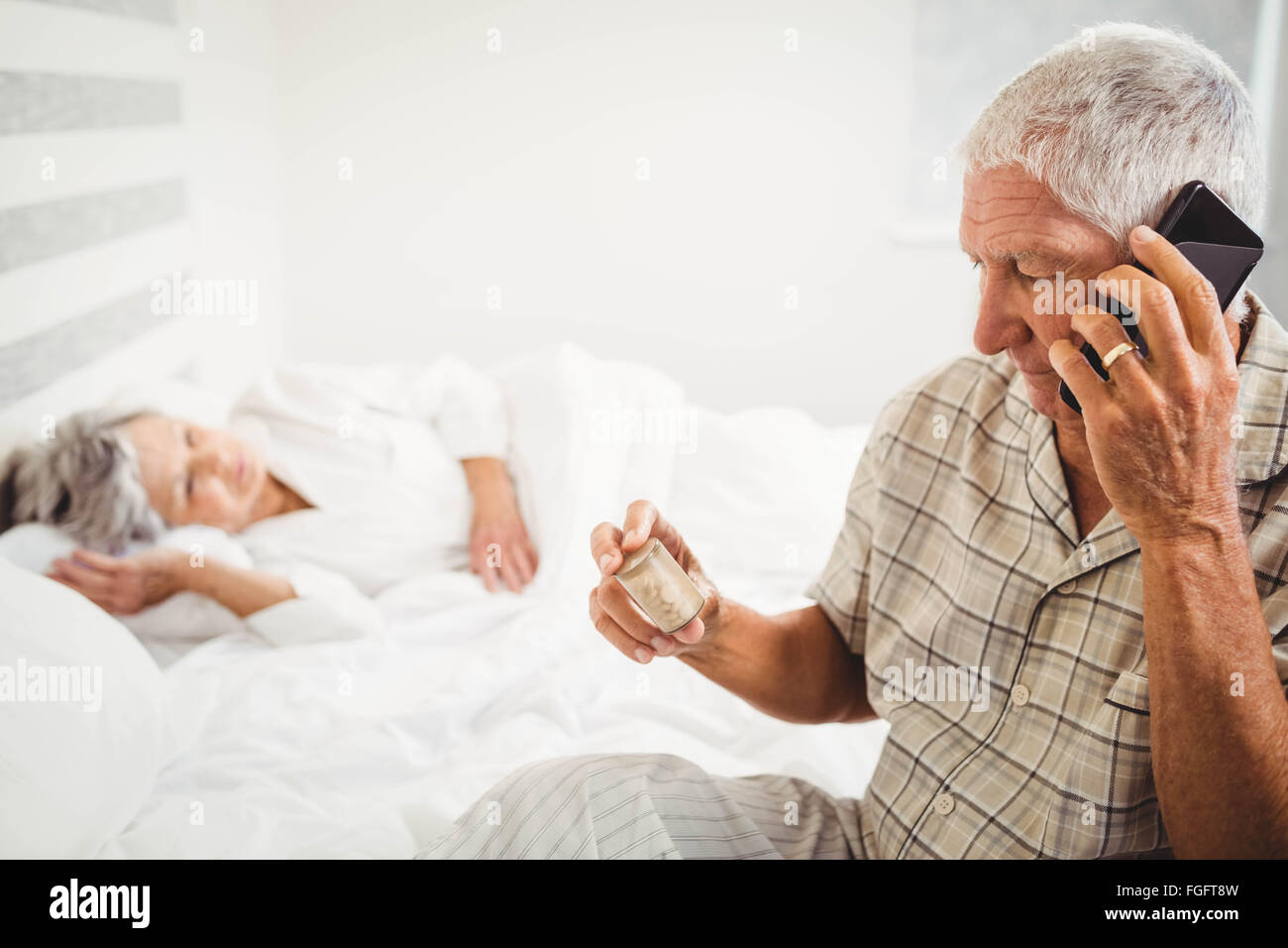 Senior man looking at pill bottle and talking on phone Stock Photo