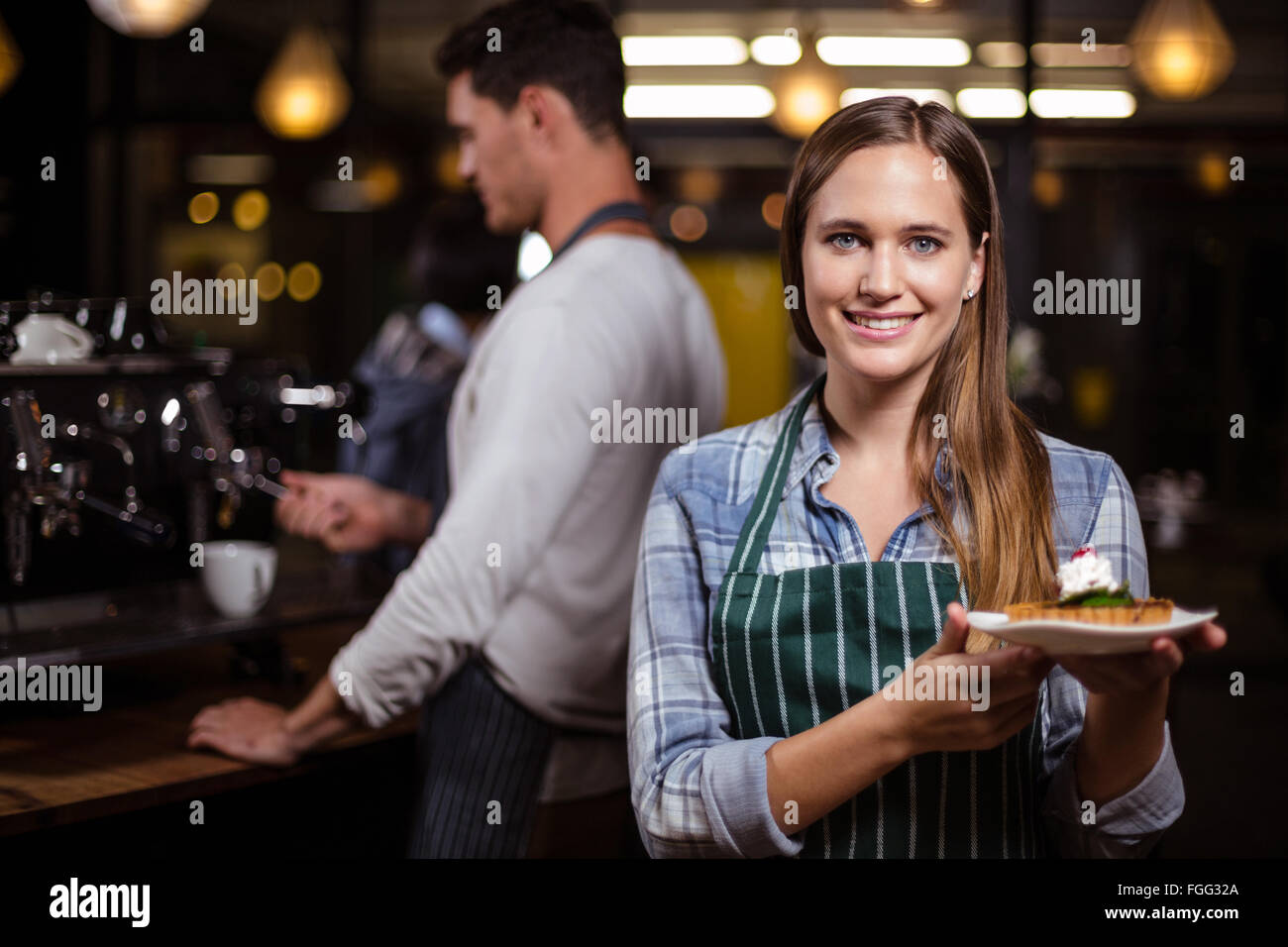 Pretty barista holding dessert and smiling at the camera Stock Photo