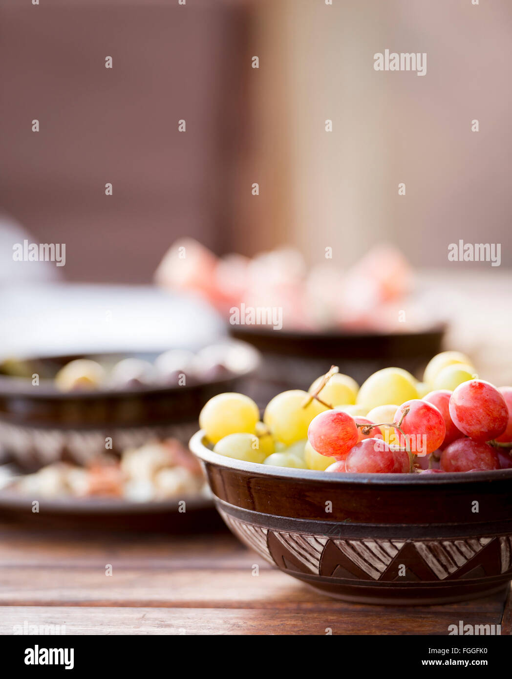 Classic antipasto food typical of the Mediterranean including grapes, olives, salami in shallow focus Stock Photo