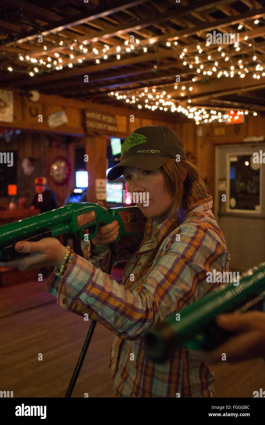 Two women laugh and play a video game in a Montana bar. Stock Photo