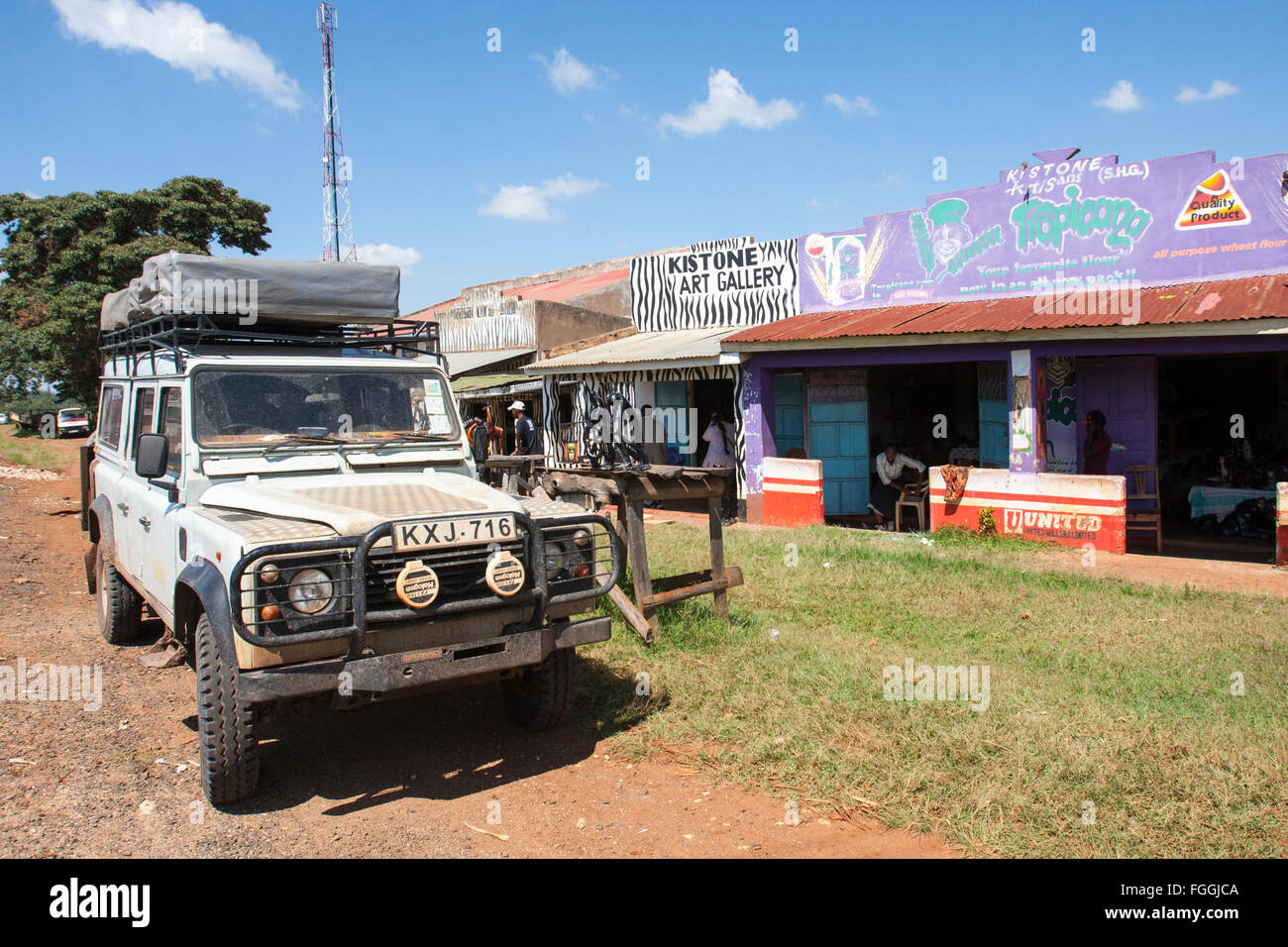 Old Land Rover Defender 110  parked outside rustic tourist art or gift shops Kistone  Kenya Stock Photo