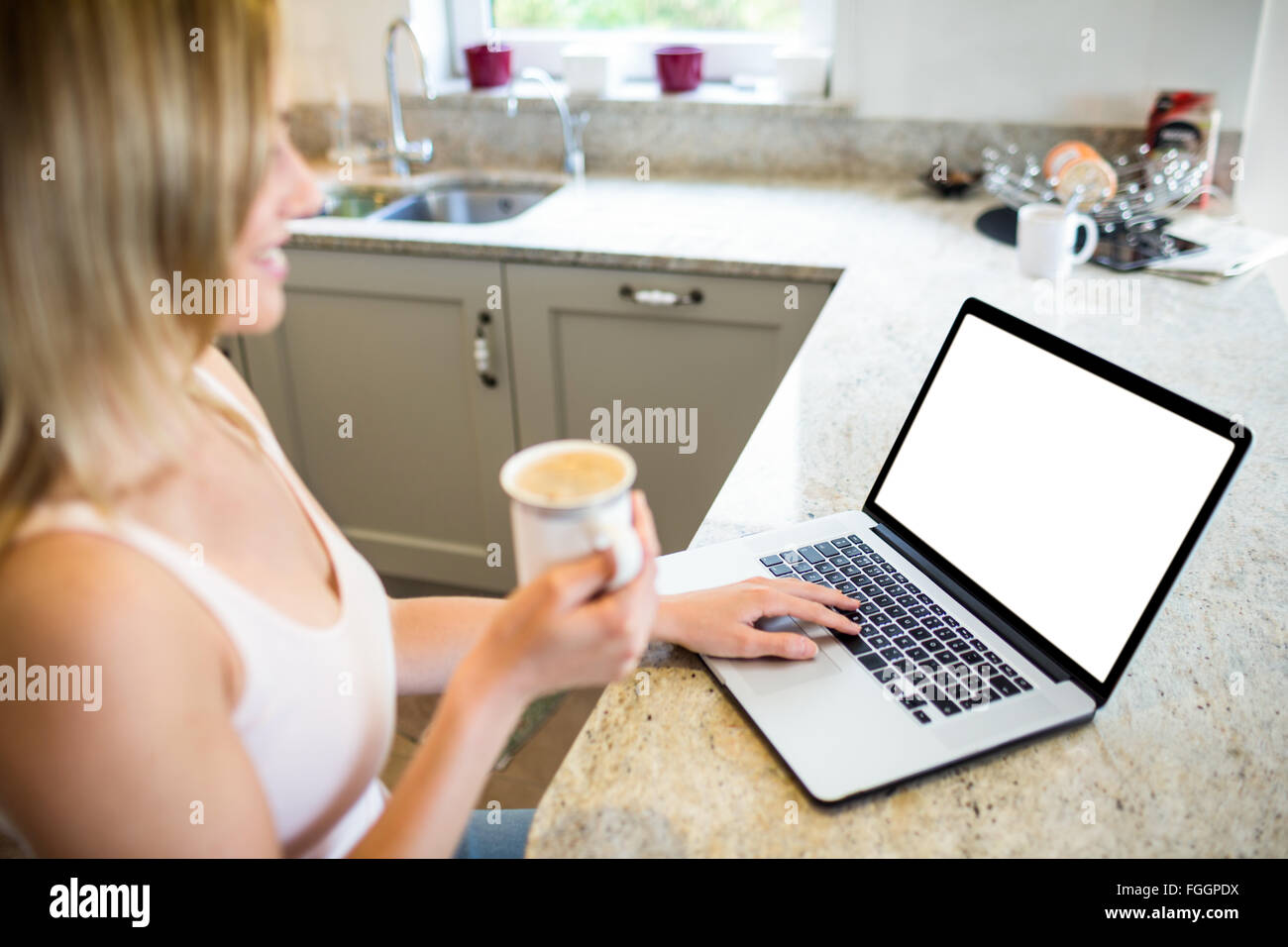 Pretty blonde woman having coffee and using laptop Stock Photo - Alamy