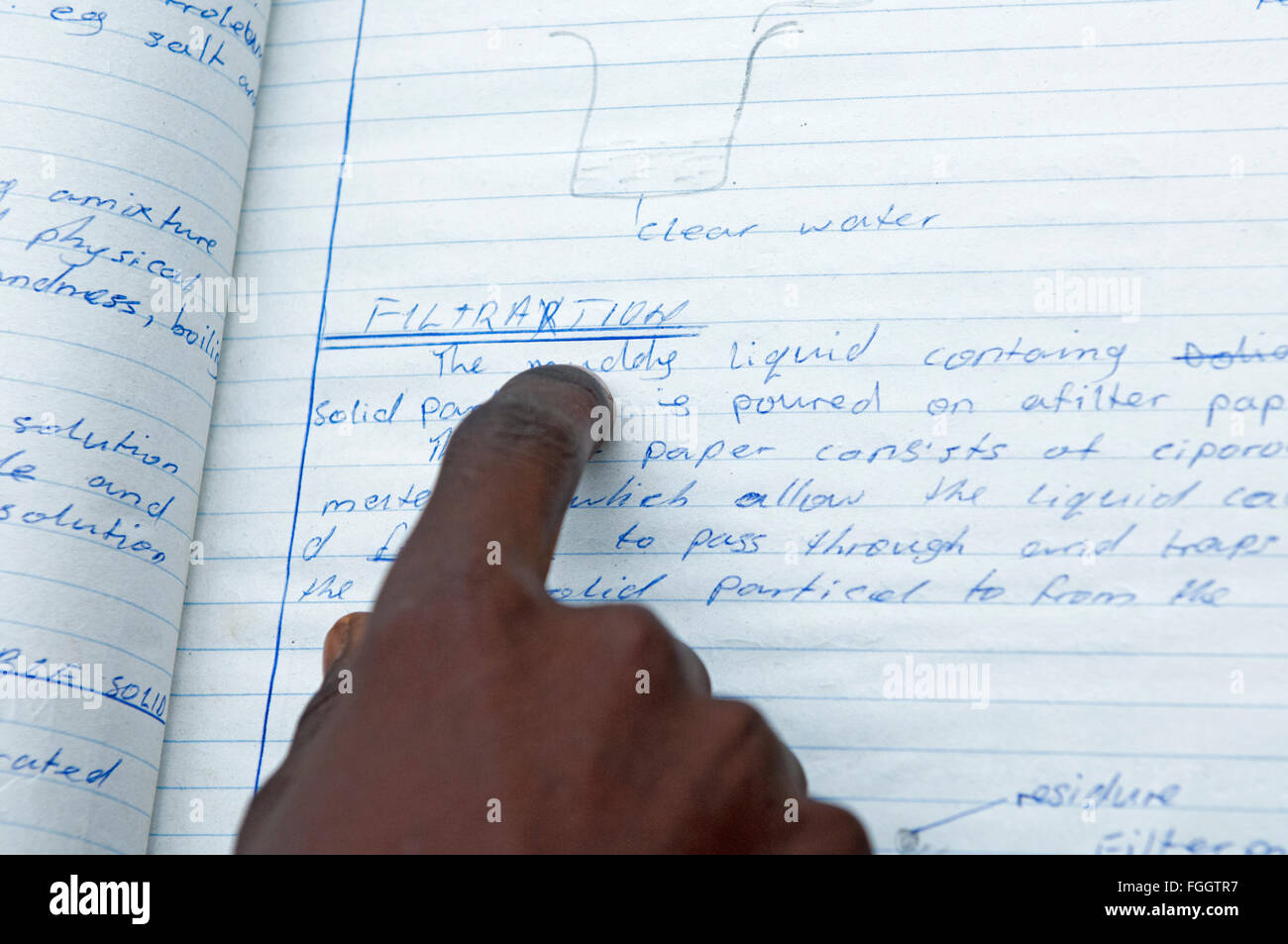 Ugandan child reading from schoolbook, using finger to follow the lines. Stock Photo