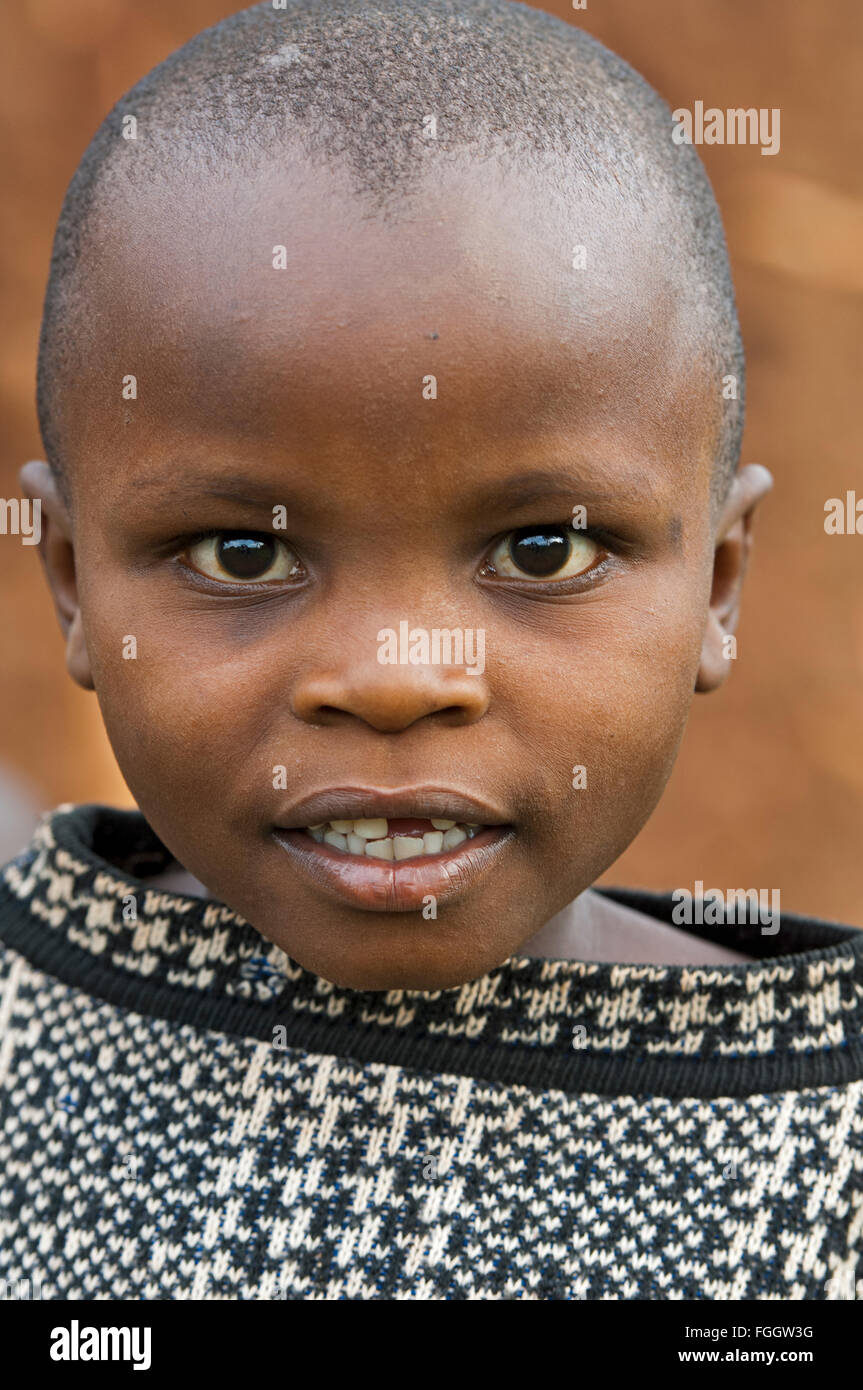Ugandan children outside their home, dressed in cast off clothing. Stock Photo