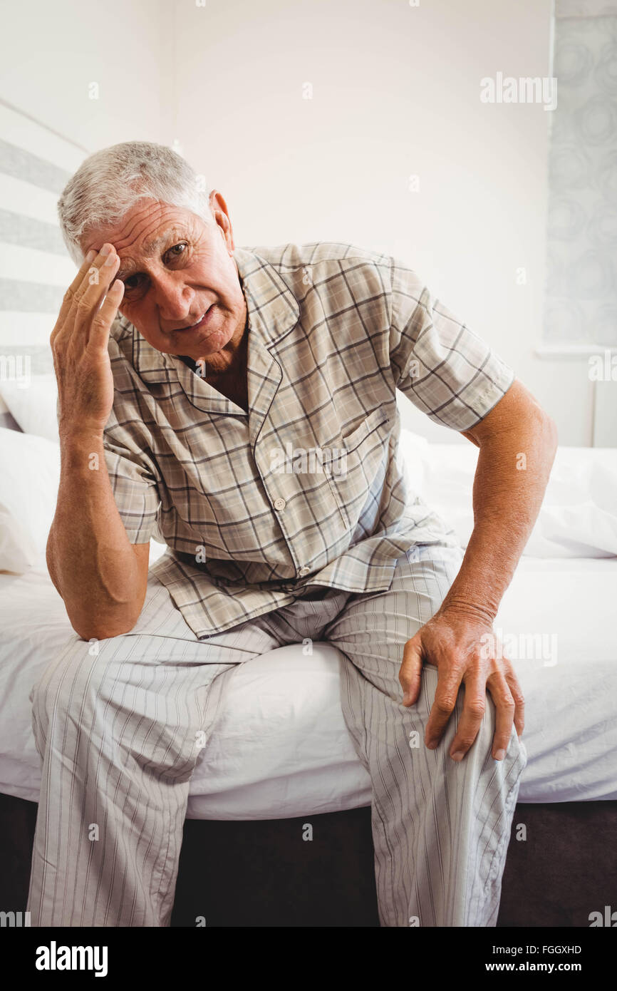 Frustrated senior man sitting on bed Stock Photo