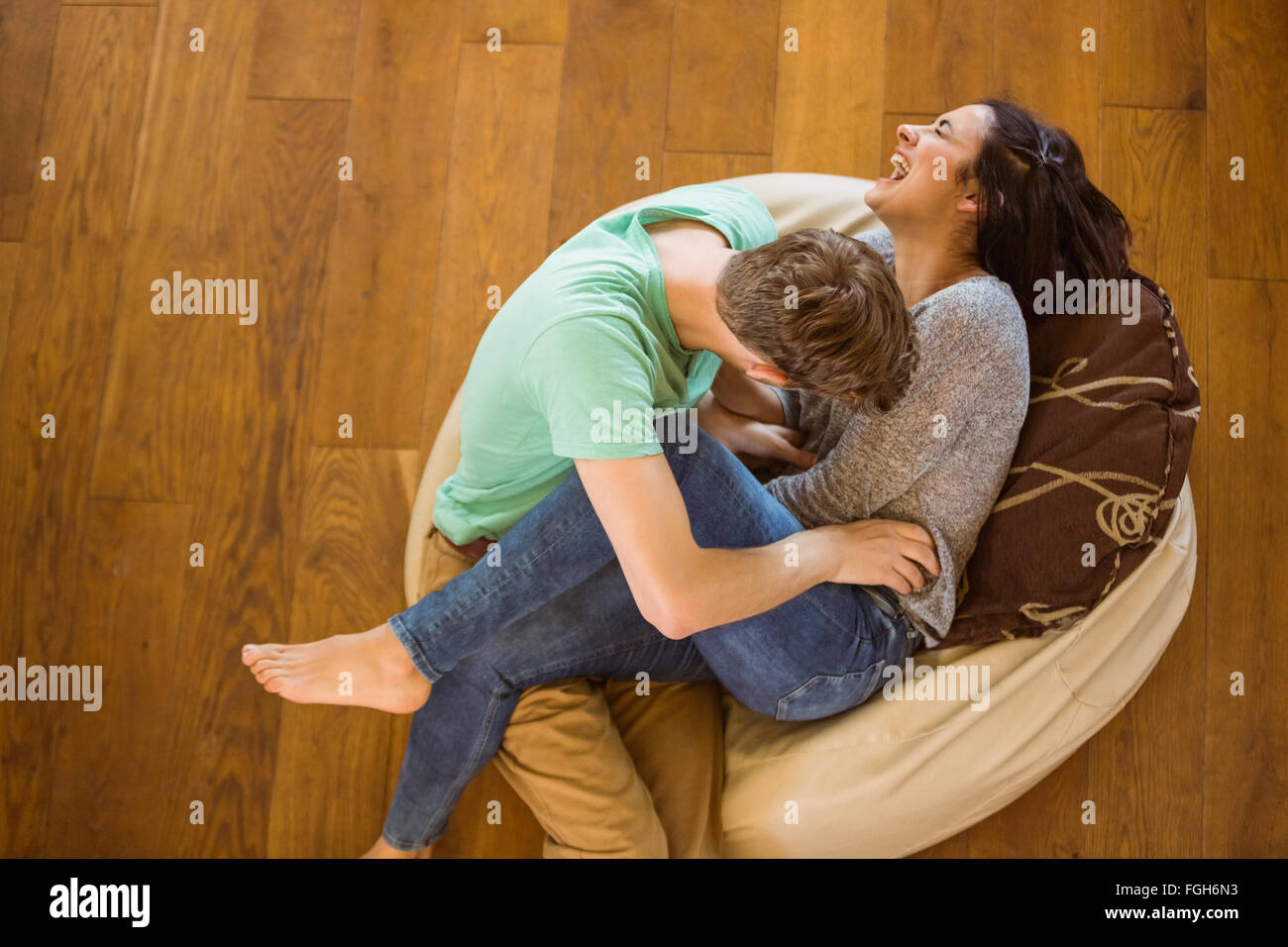 Cute couple laughing together on beanbag Stock Photo