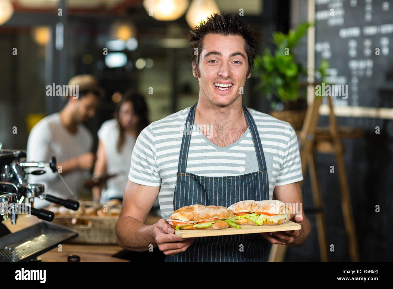 Smiling barista holding sandwiches Stock Photo