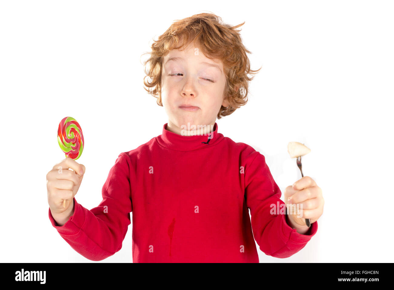 boy holding candy and fruit decide between healthy and unhealthy Stock Photo