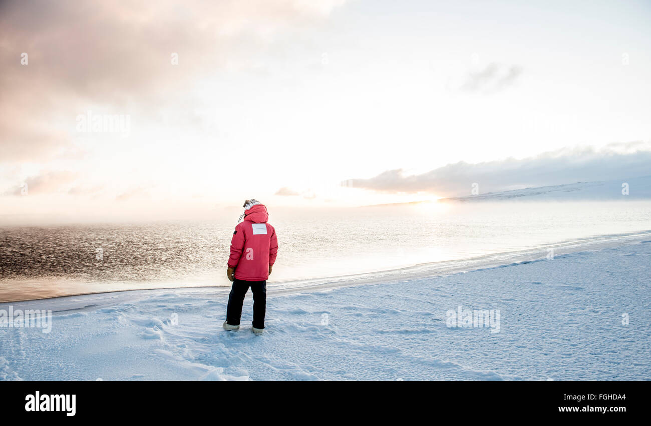A man watches the sunrise over the water of the Ross Sea, Antarctica. Stock Photo