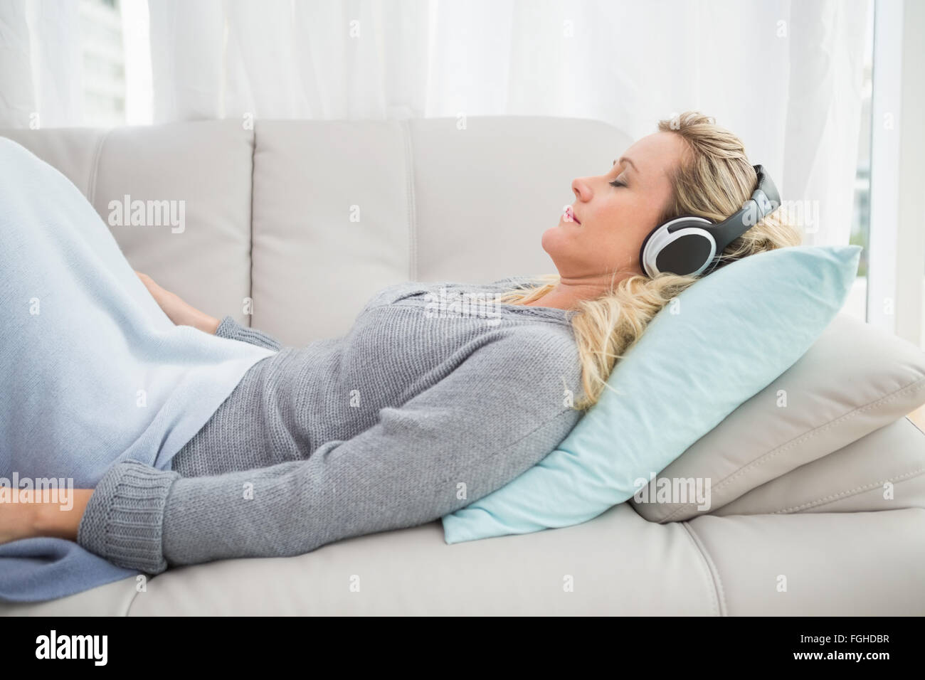 Happy girl listening to music lying on the couch Stock Photo - Alamy
