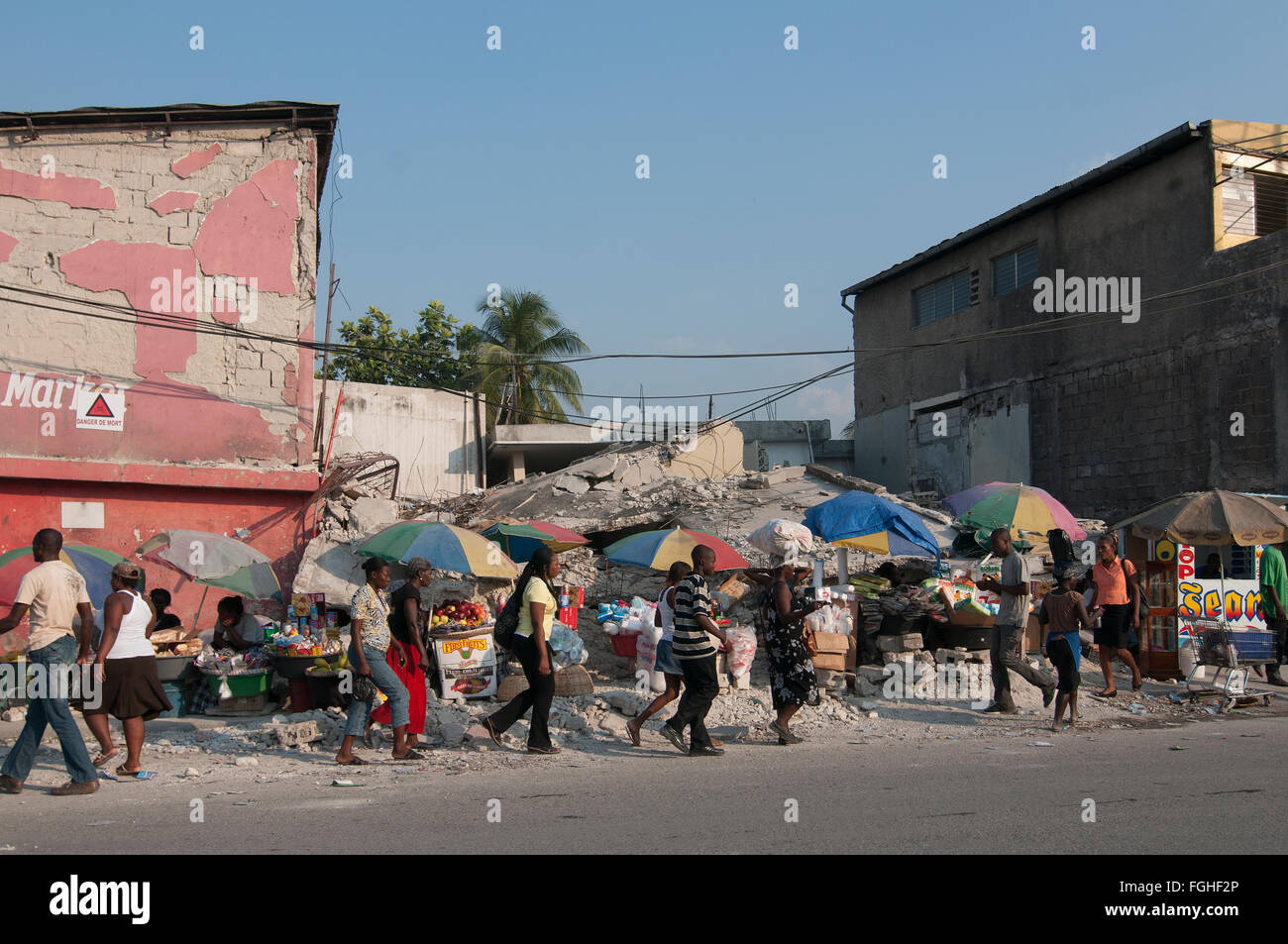 Pedestrians walk past a building that collapsed in Port-au-Prince after a 7.0 magnitude earthquake struck Haiti on 12 January 2010 Stock Photo