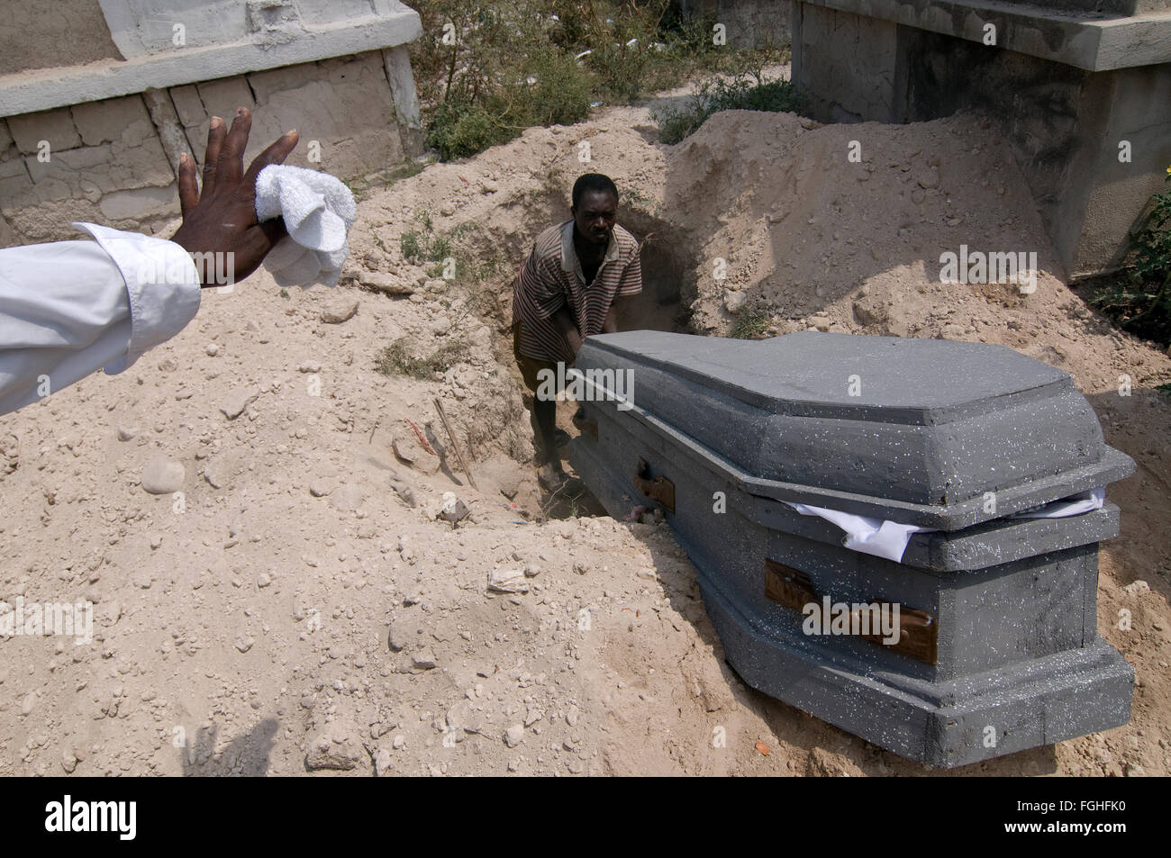 A man lower a coffin into a grave in a cemetery in the suburb area of Port-au-Prince, Haiti Stock Photo