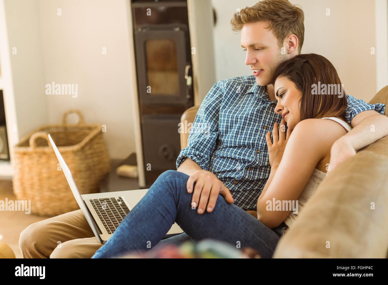 Happy young couple relaxing on the couch with laptop Stock Photo - Alamy