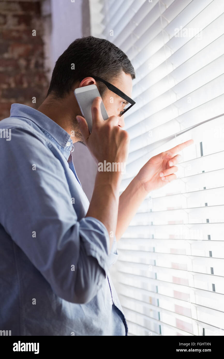 Businessman Using Mobile Phone While Looking Through Blinds In Office Stock Photo Alamy