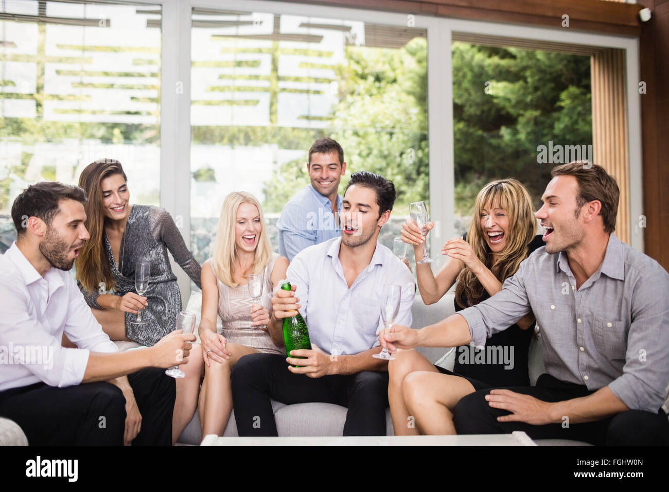 Man popping champagne bottle with friends Stock Photo