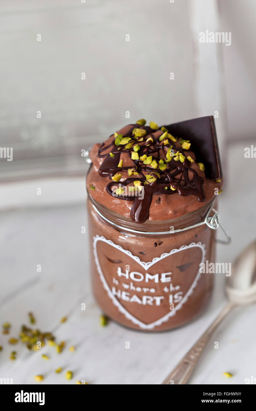 Vegan chocolate banana ice cream with melted dark chocolate and pistachios in a jar Stock Photo