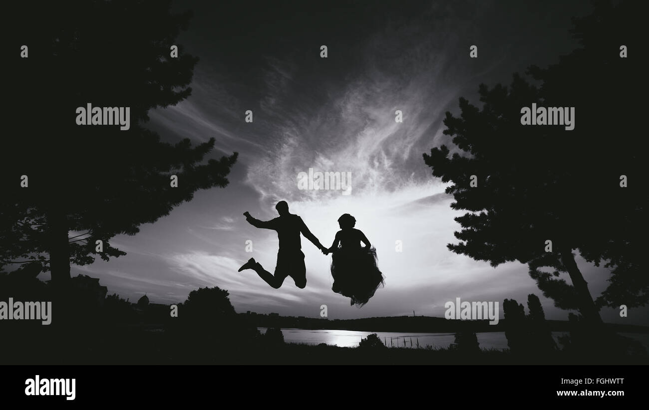 groom and bride jumping against the beautiful sky Stock Photo - Alamy