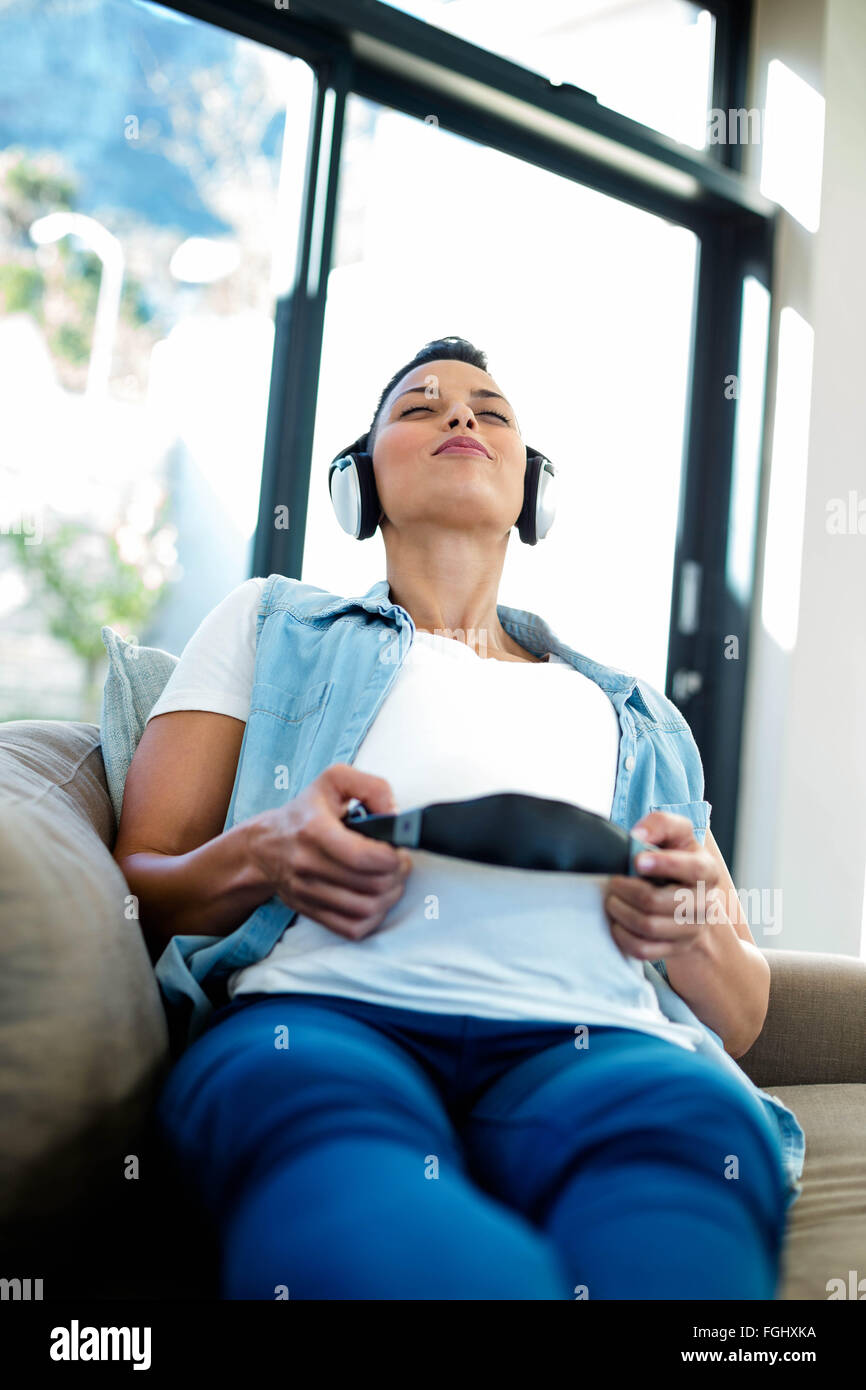 Pregnant woman listening to music on sofa Stock Photo - Alamy