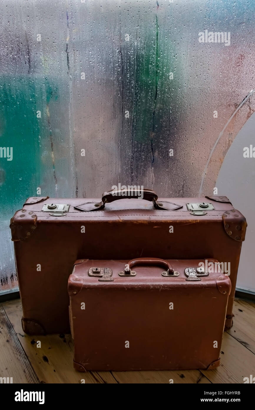 Retro brown leather suitcases in front of a steamy cafe window on a rainy afternoon Stock Photo