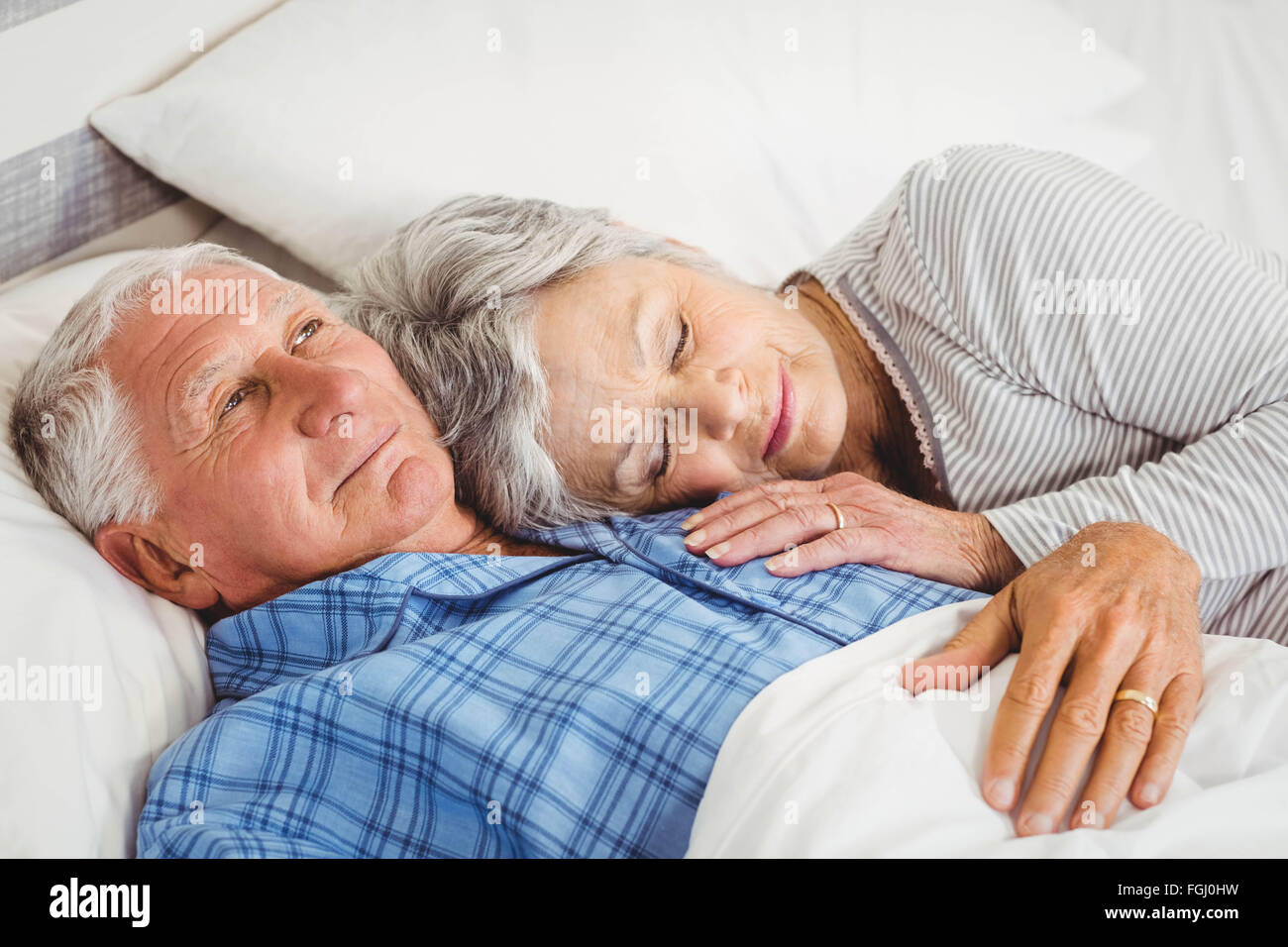 Senior man lying awake next to asleep senior woman Stock Photo