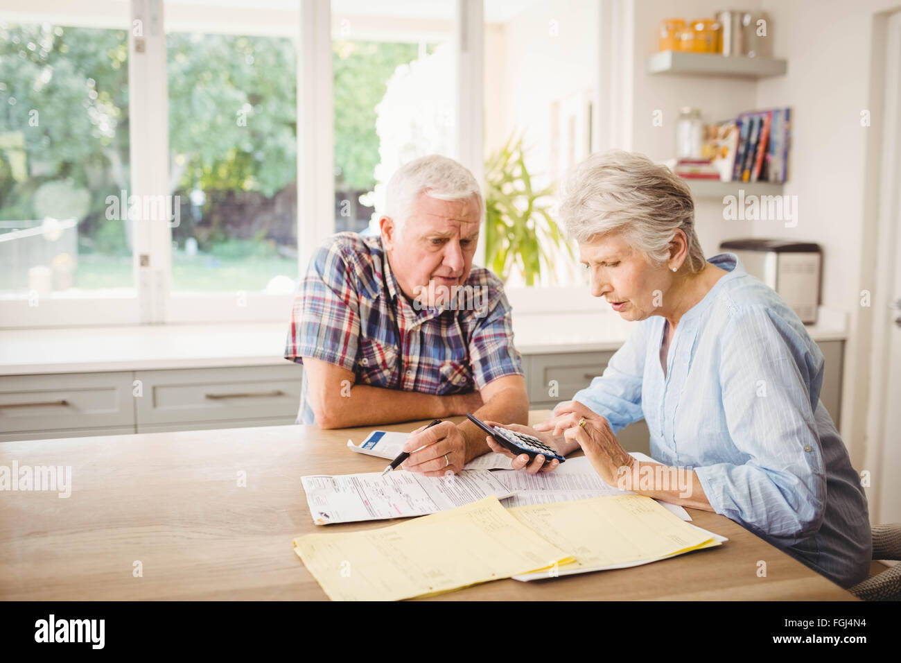 Worried senior couple checking their bills Stock Photo