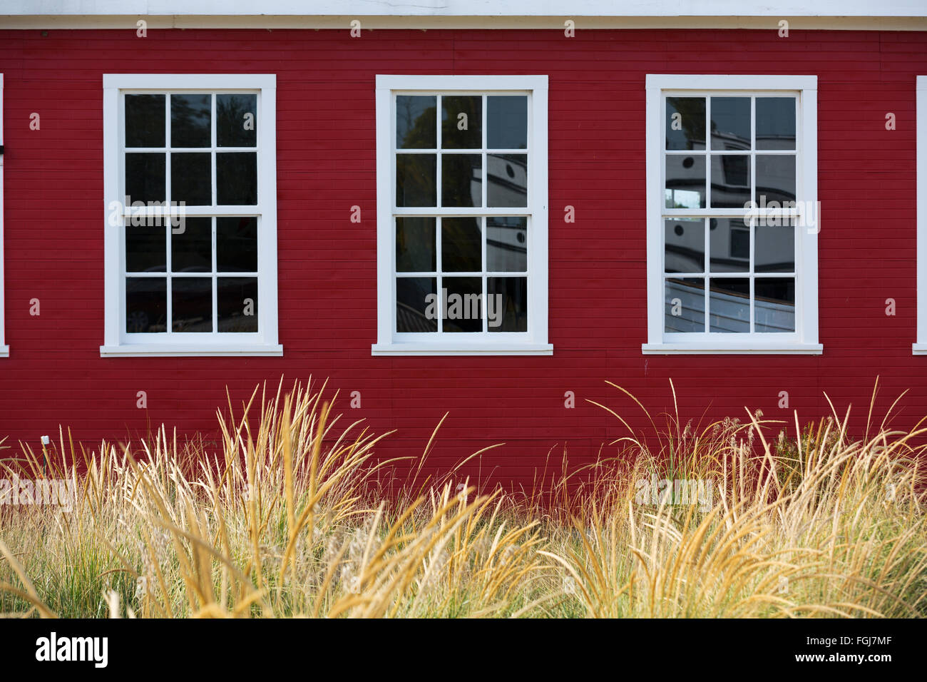 White Cape Cod Windows on red building with dune grass at Glen Haven Michigan Stock Photo