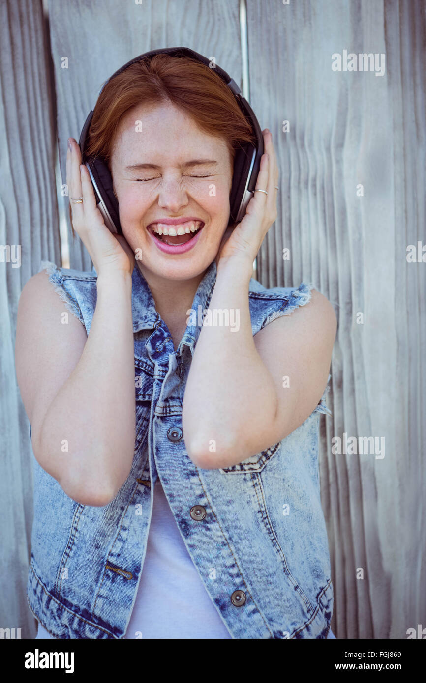 smiling hipster woman listening to loud music through headphones Stock Photo