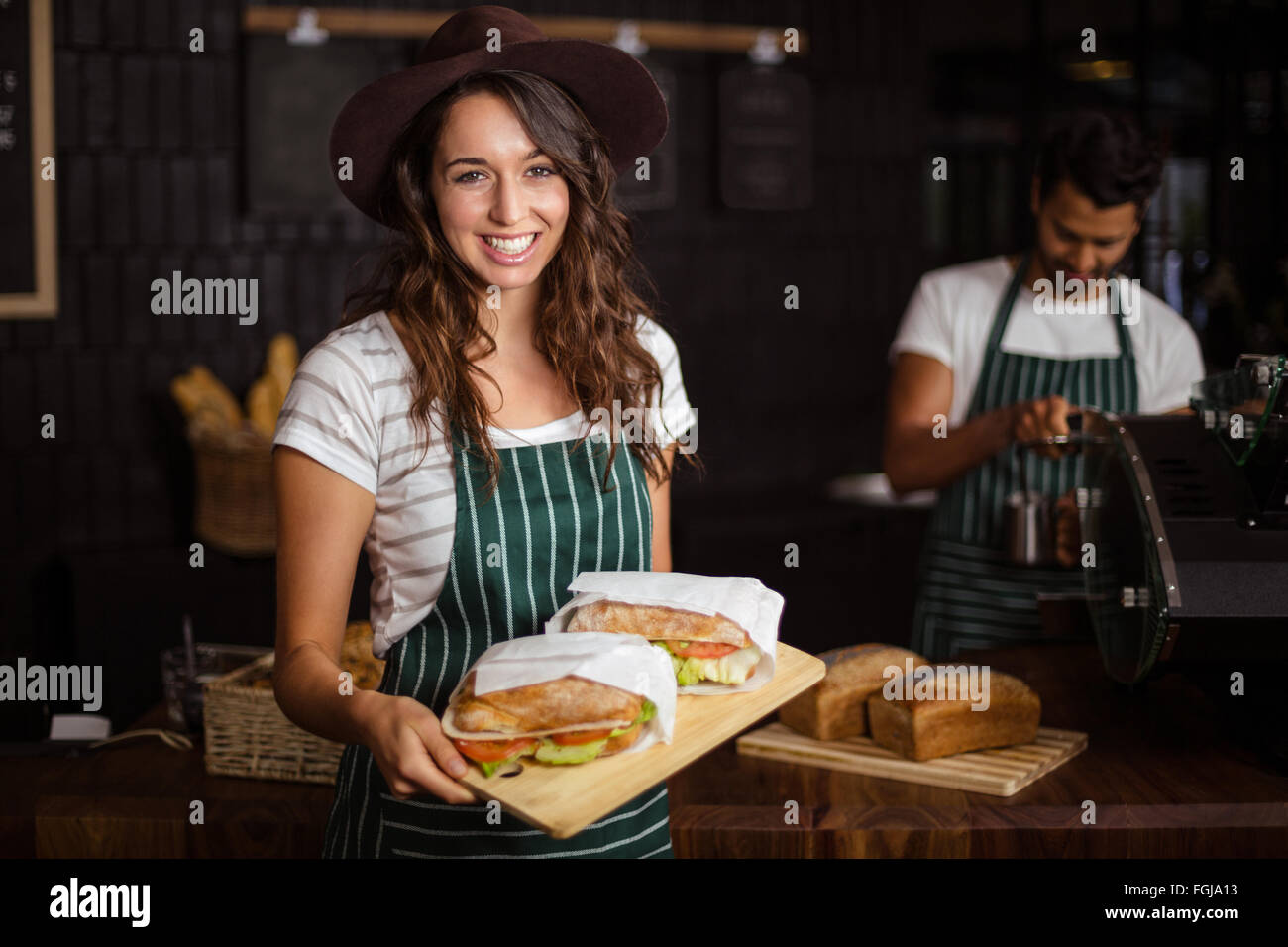 Smiling barista holding sandwiches Stock Photo