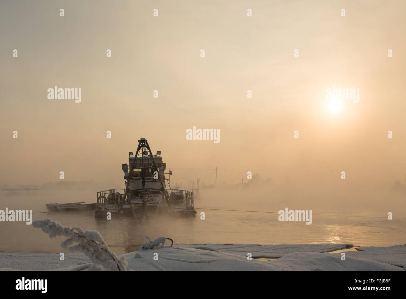 a dredger boat in winter mist at sunset Stock Photo