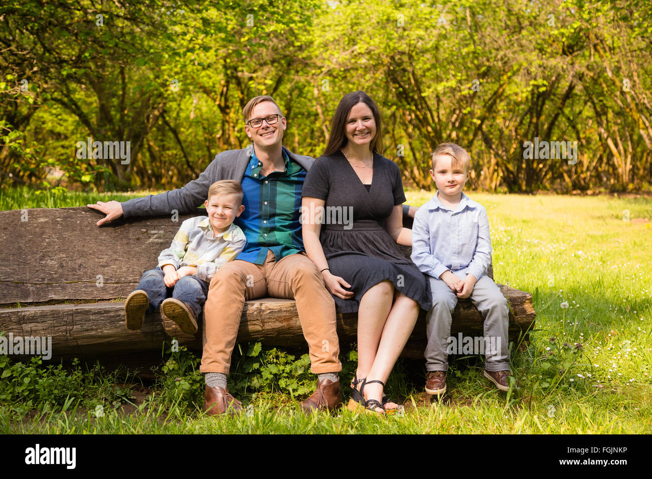 Family of four outdoors in a natural setting with nice light in a lifestyle portrait. Stock Photo