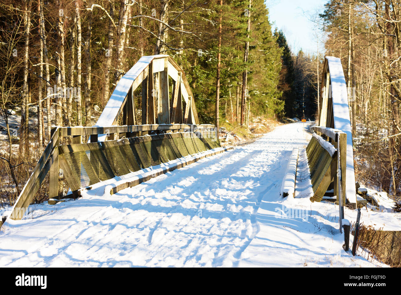 An old iron railway bridge now used as a walk and cycle path through the forest. It is winter and some snow is on the ground. We Stock Photo