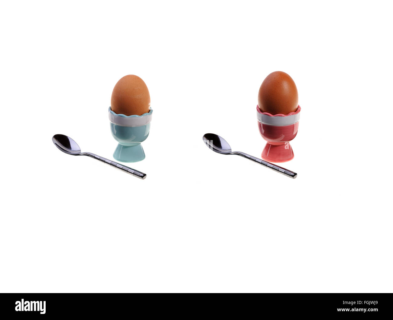 Two egg cups, eggs and spoons. Stock Photo