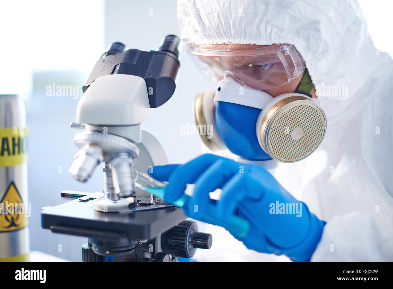 Modern chemist in protective clothing analyzing characteristics of toxic fluid in laboratory Stock Photo