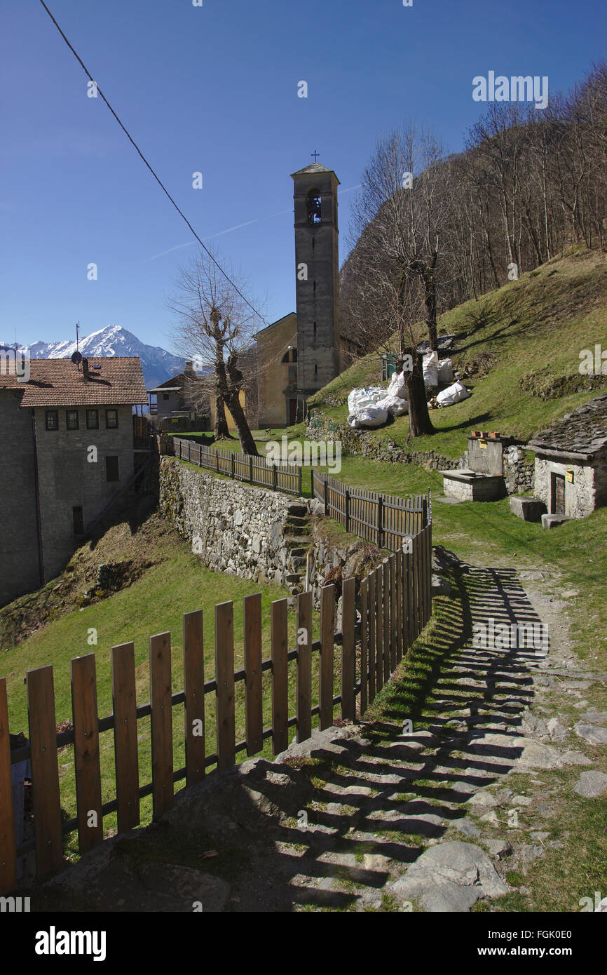 Fence, path and church tower in Frasnedo, Valle dei Ratti, Italy Stock Photo