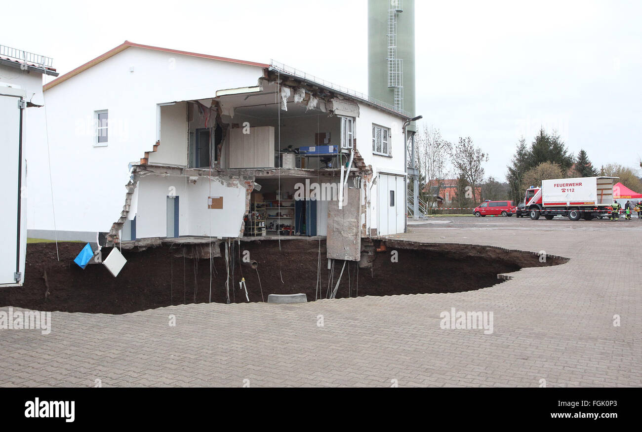 Nordhausen, Germany. 20th Feb, 2016. A sinkhole pictured between two damaged buildings on the former compound of the civil protection agency (Katastrophenschutz) in Nordhausen, Germany, 20 February 2016. The sinkhole reportedly opened late 19 February evening between the two uninhabitated buildings and left a crater with a depth of some 50 metres. The hole has filled with water since then, nobody was hurt in the incident. Photo: SEBASTIAN WILLNOW/dpa/Alamy Live News Stock Photo