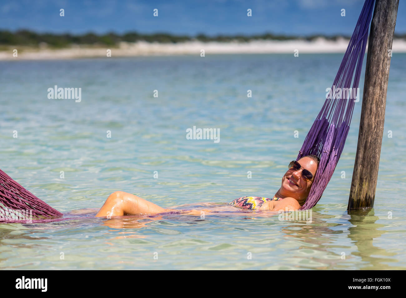 Beautiful woman at beach, relaxing on a net under water Stock Photo