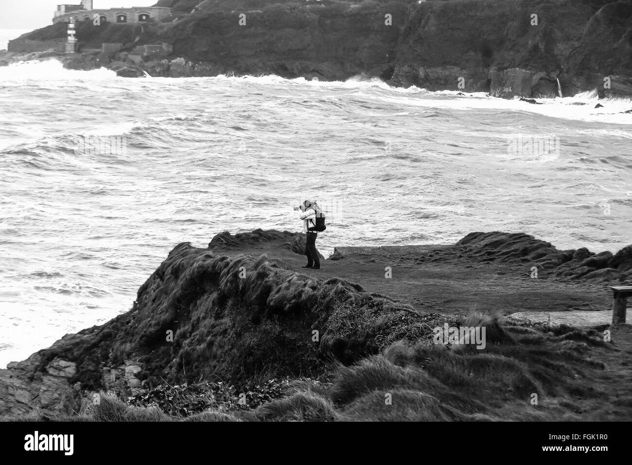 Lone photographer on cliff top in stormy weather Stock Photo