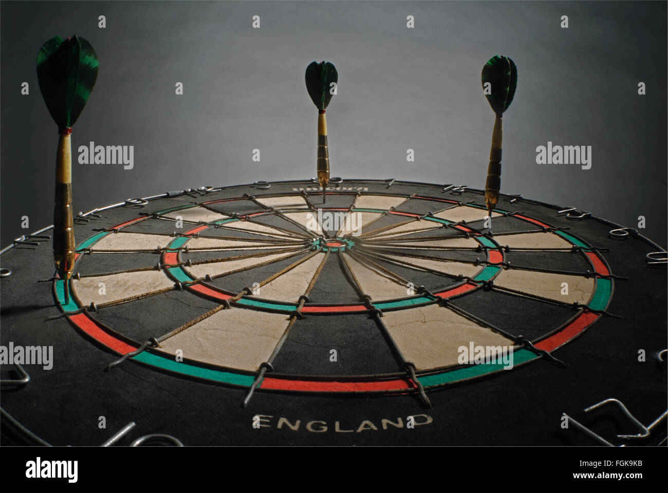 Three oldfashioned darts with feather flights in a dartboard, looking