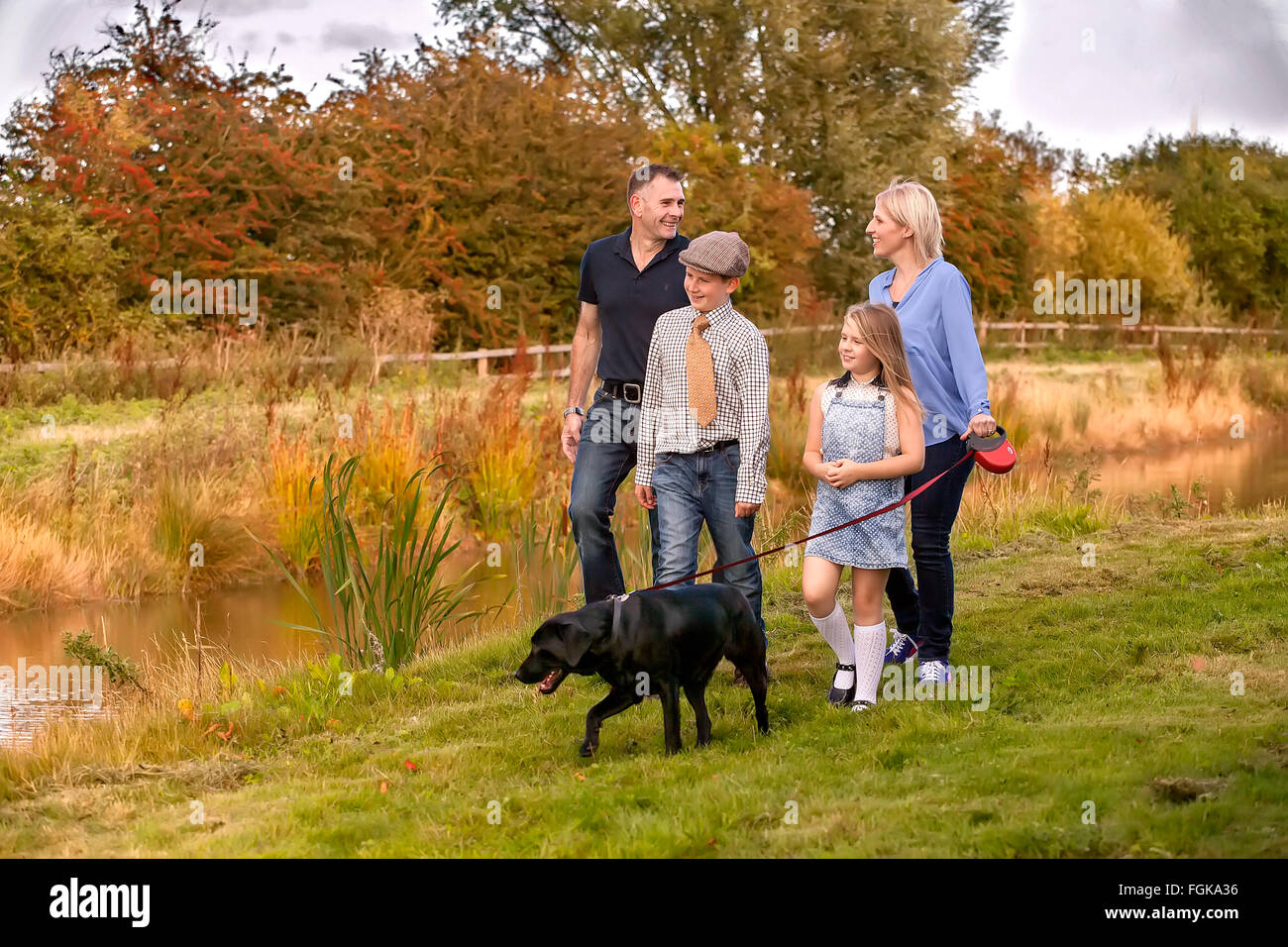 Family walking with dog on lead by waterway. Stock Photo