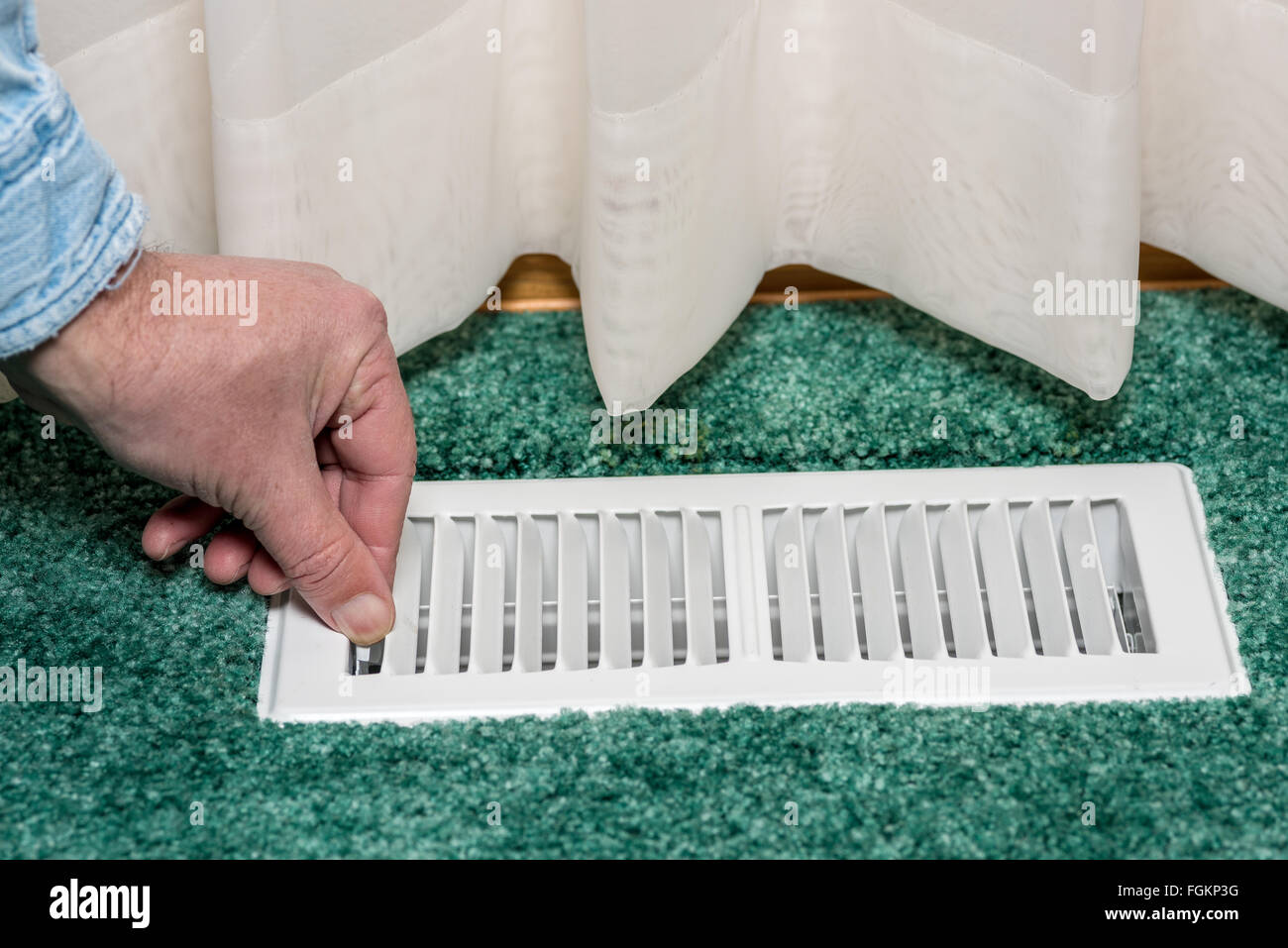 Adjusting the louvers of a floor register Stock Photo