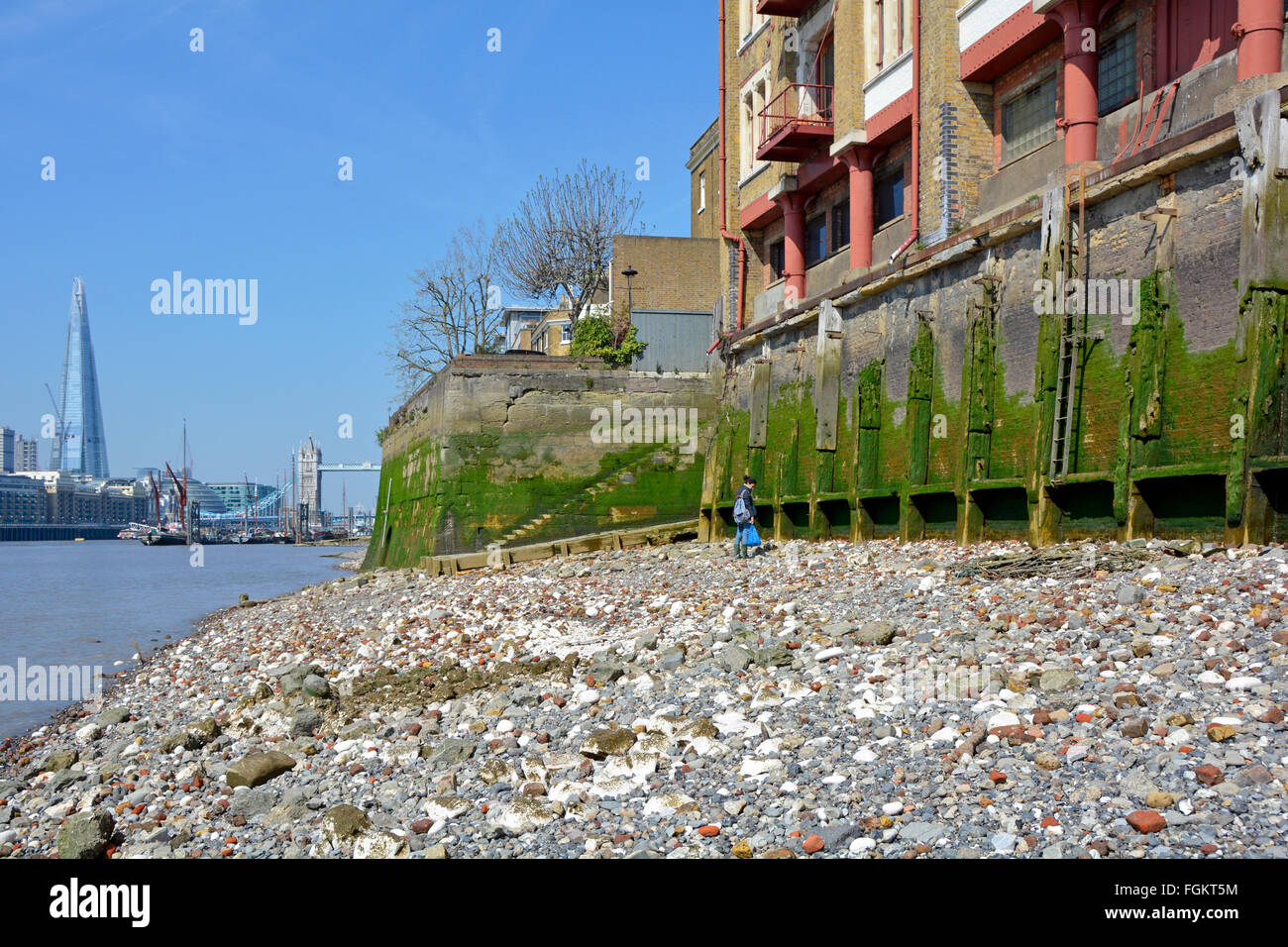 Wapping & River Thames foreshore at low tide shows old base walls of  riverside warehouse buildings with Tower Bridge & Shard beyond London England UK Stock Photo