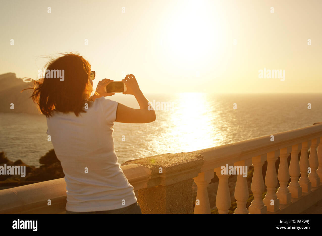 Girl photographing sunset with her phone Stock Photo
