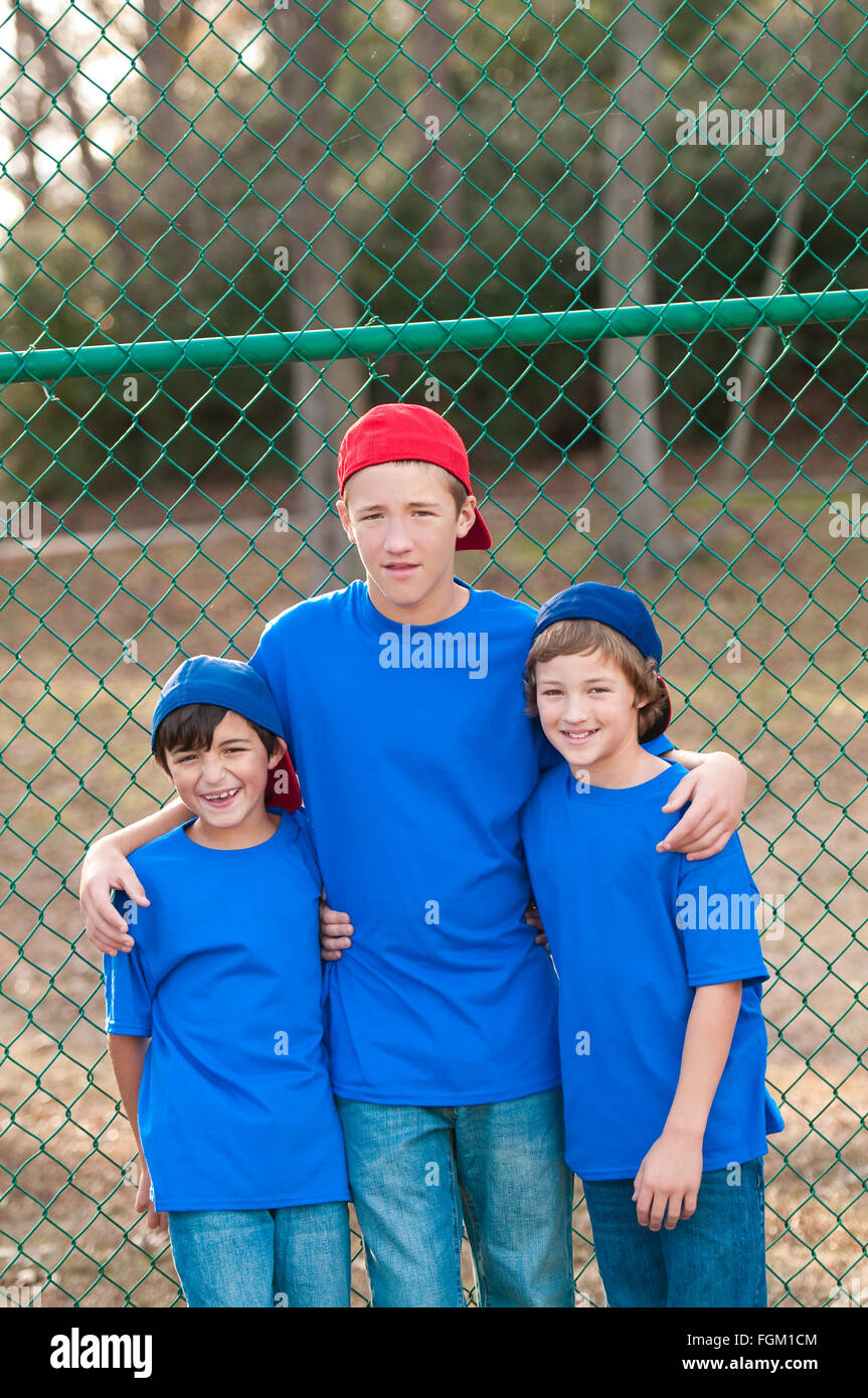 Outdoor portrait of group of three boys that are friends posing after playing backyard baseball. Stock Photo
