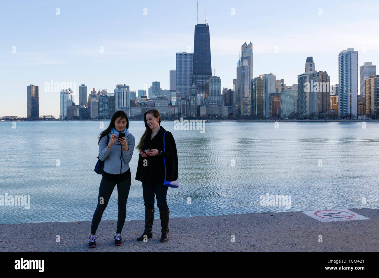 Chicago, USA 20th February 2016. Two young women on the North Avenue Beach Seawall. Chicagoans and visitors alike came to the city's lakeshore to enjoy an unseasonably warm day with temperatures over 60ºF/15ºC. The high winds that blasted the city yesterday subsided to a gentle breeze. Credit:  Todd Bannor/Alamy Live News Stock Photo