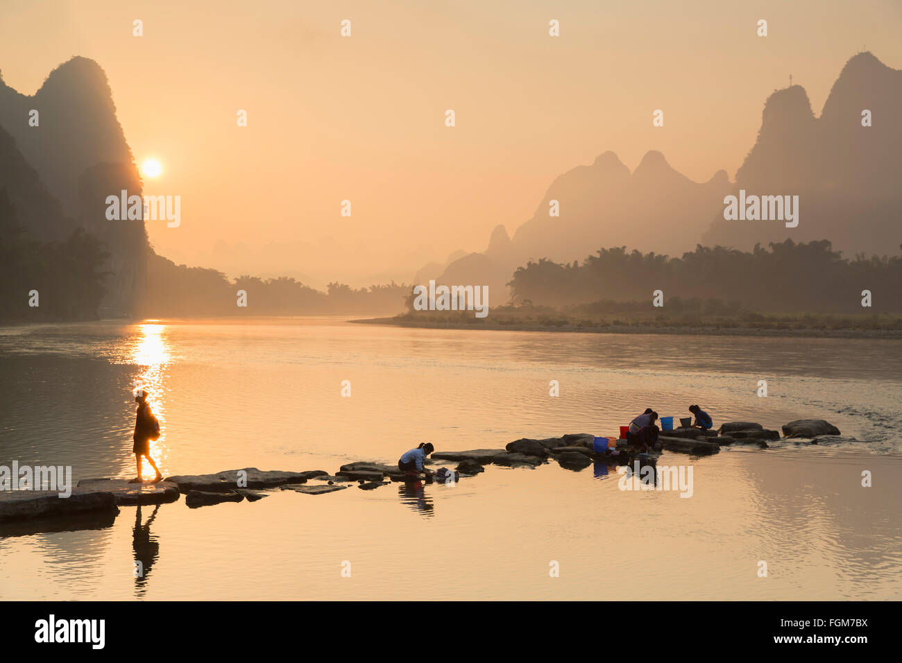 Women washing clothes in Li River at dawn, Xingping, Yangshuo, Guangxi, China Stock Photo