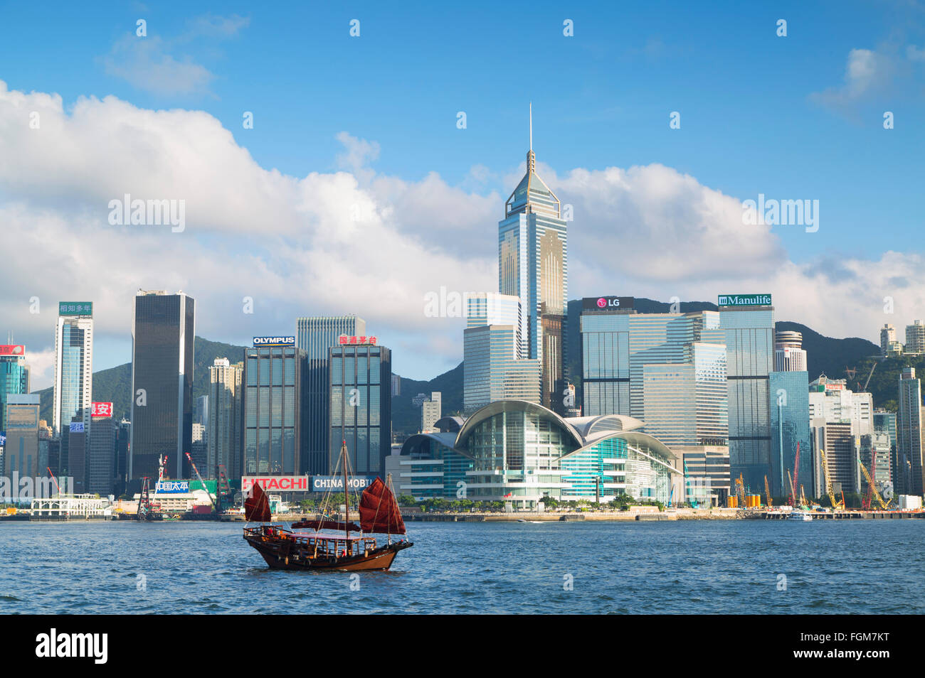 Junk boat passing Convention Centre and Hong Kong Island skyline, Hong Kong, China Stock Photo