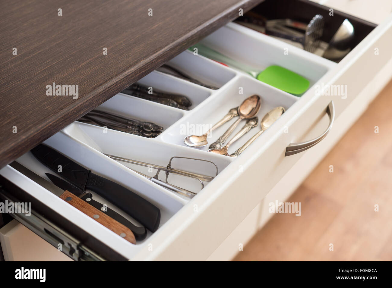 Spoons, forks and knives in cutlery box drawer in kitchen cupboard