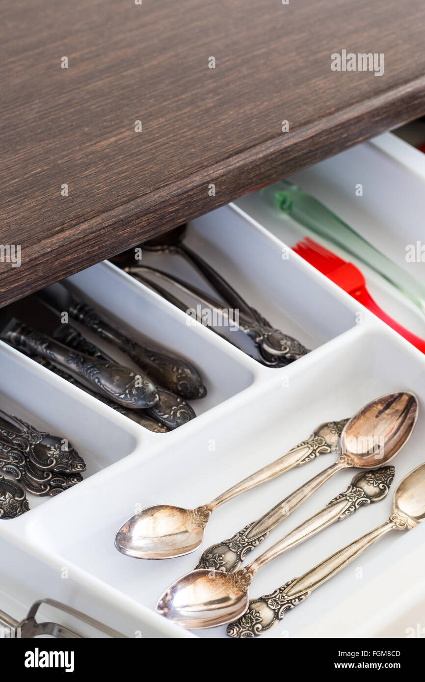 Spoons, forks and knives in cutlery box drawer in kitchen cupboard