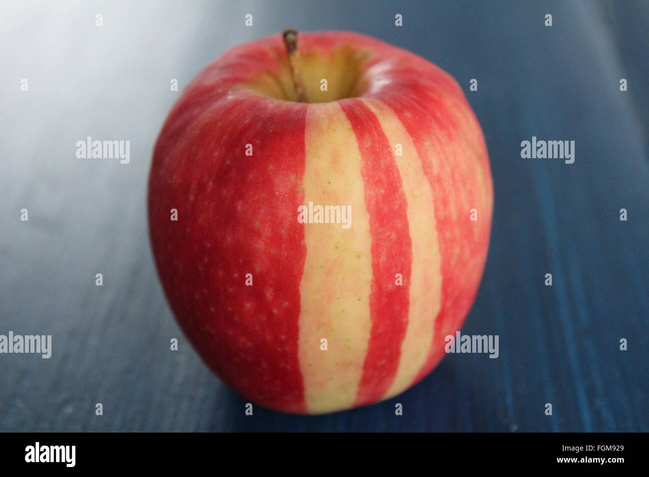 Striped red apple on blue table Stock Photo