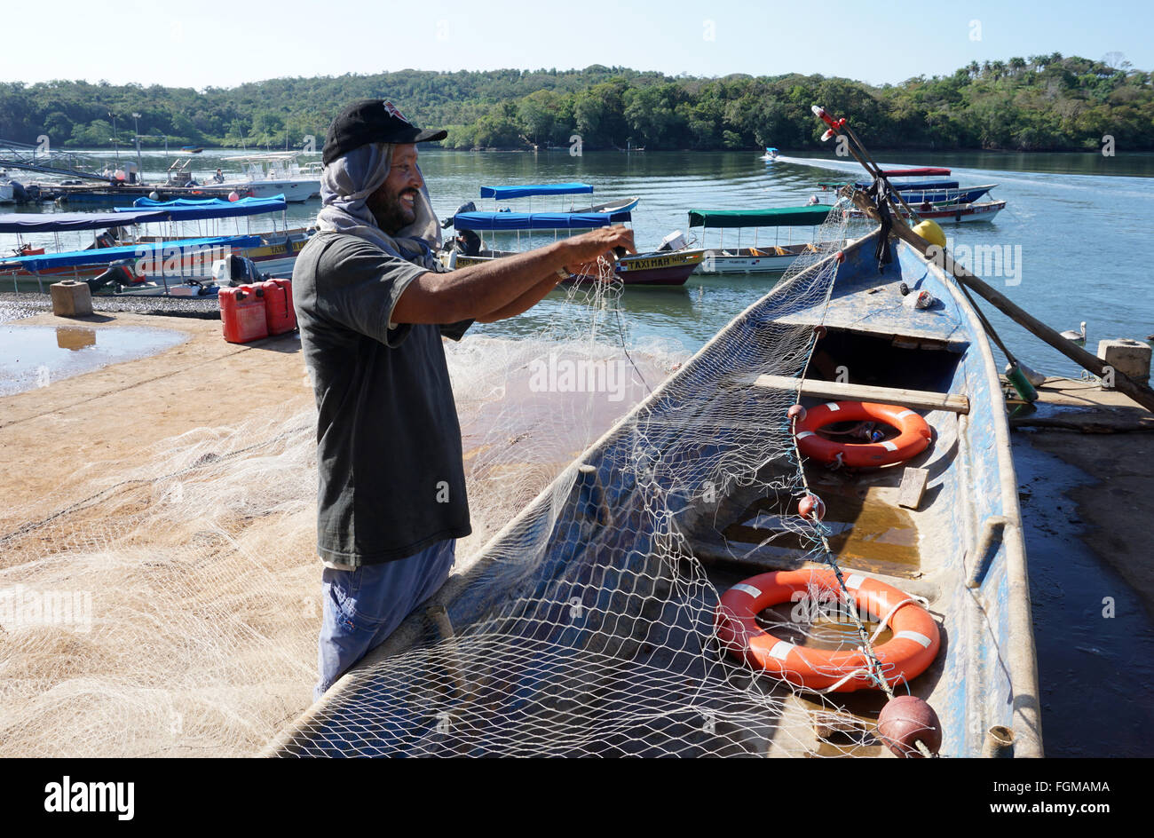Fisherman repairing his net at Boca Chica,Chiriqui Panama.Near Isla Boca Brava,which you see across the water. Stock Photo